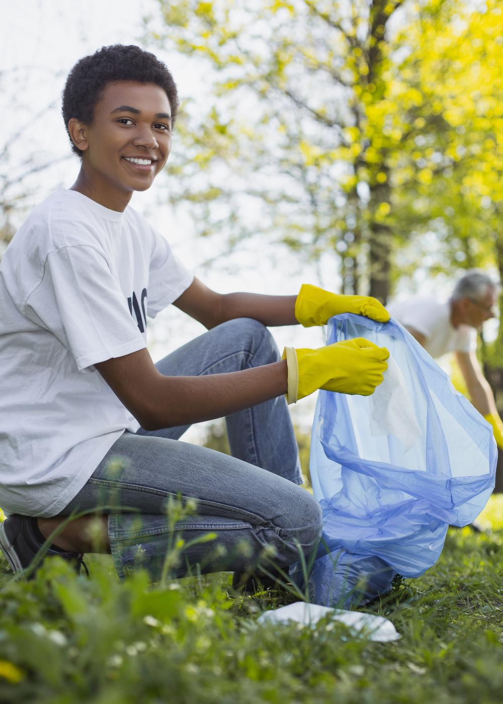 Boy holding a bag wearing white shirt and yellow gloves.